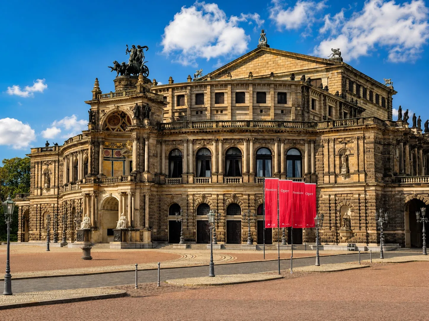 Semperoper in Dresden bei Sonnenschein mit roten Premierenfahnen